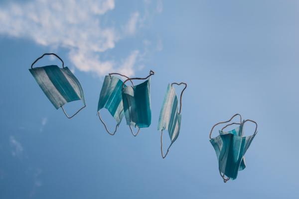 Five blue disposable masks flying in the air